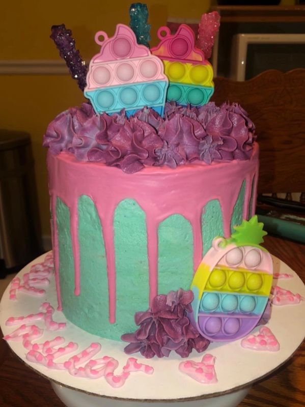 A 3 layered vanilla cake topped with vanilla buttercream, white chocolate drip, rock candy, etc.