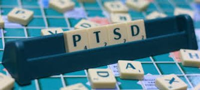 Scrabble tiles spelling out PTSD on a game board.