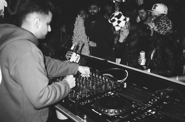 A DJ performs at a lively nighttime event with an engaged crowd.