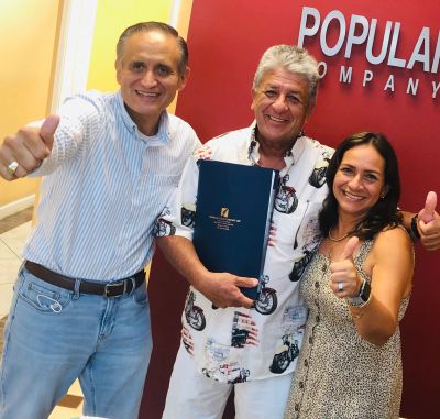 Three smiling people giving thumbs up in an office.