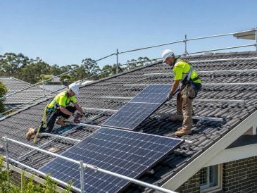 Workers installing solar panels on a roof.