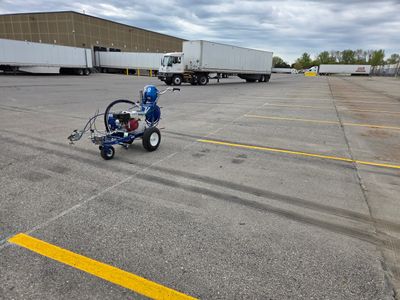 A parking lot with a line painting machine and freshly painted yellow lines.
