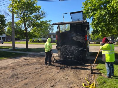 Workers paving a road with asphalt on a sunny day.