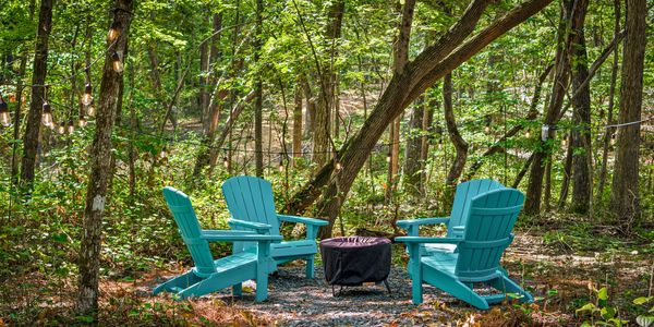 Campfire surrounded by Adirondack chairs and string lights 