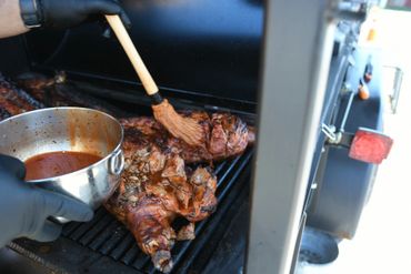 Basting meat on a grill with sauce using a brush.
