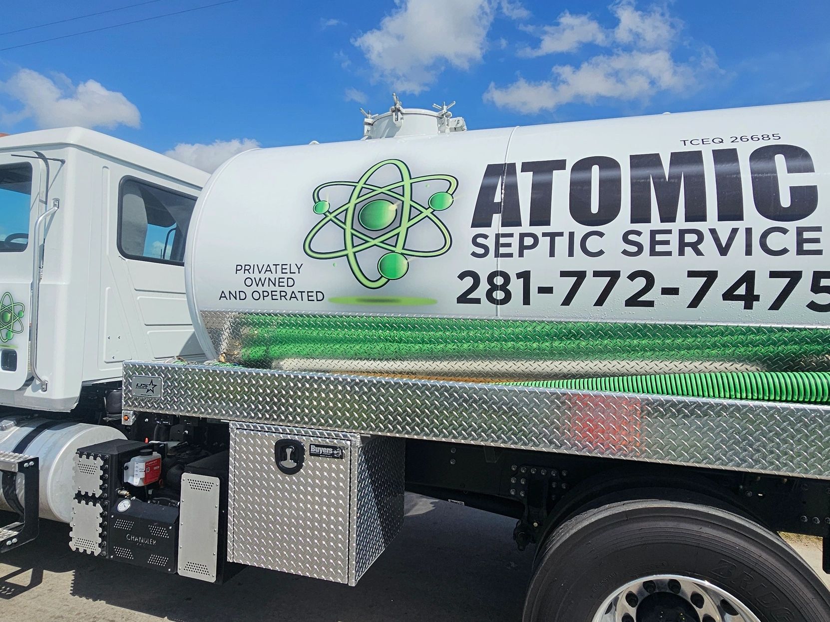 White septic service truck with green hoses and Atomic Septic Service branding.