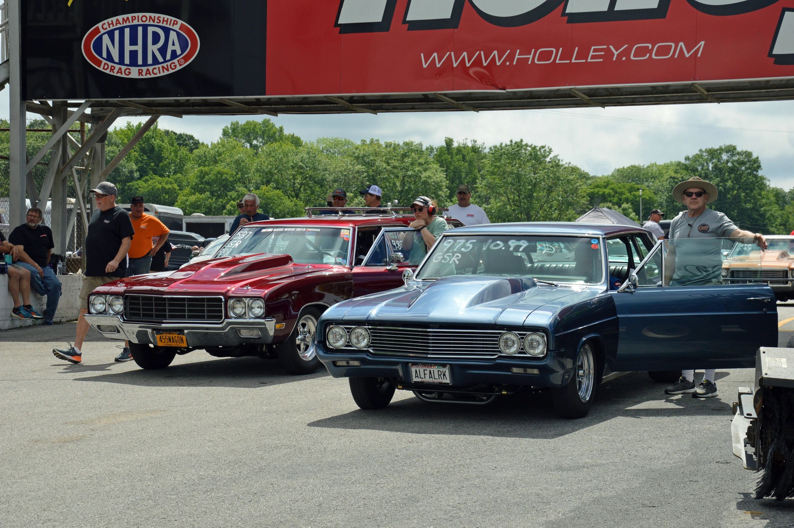 Classic muscle cars and racers at an NHRA drag racing event.