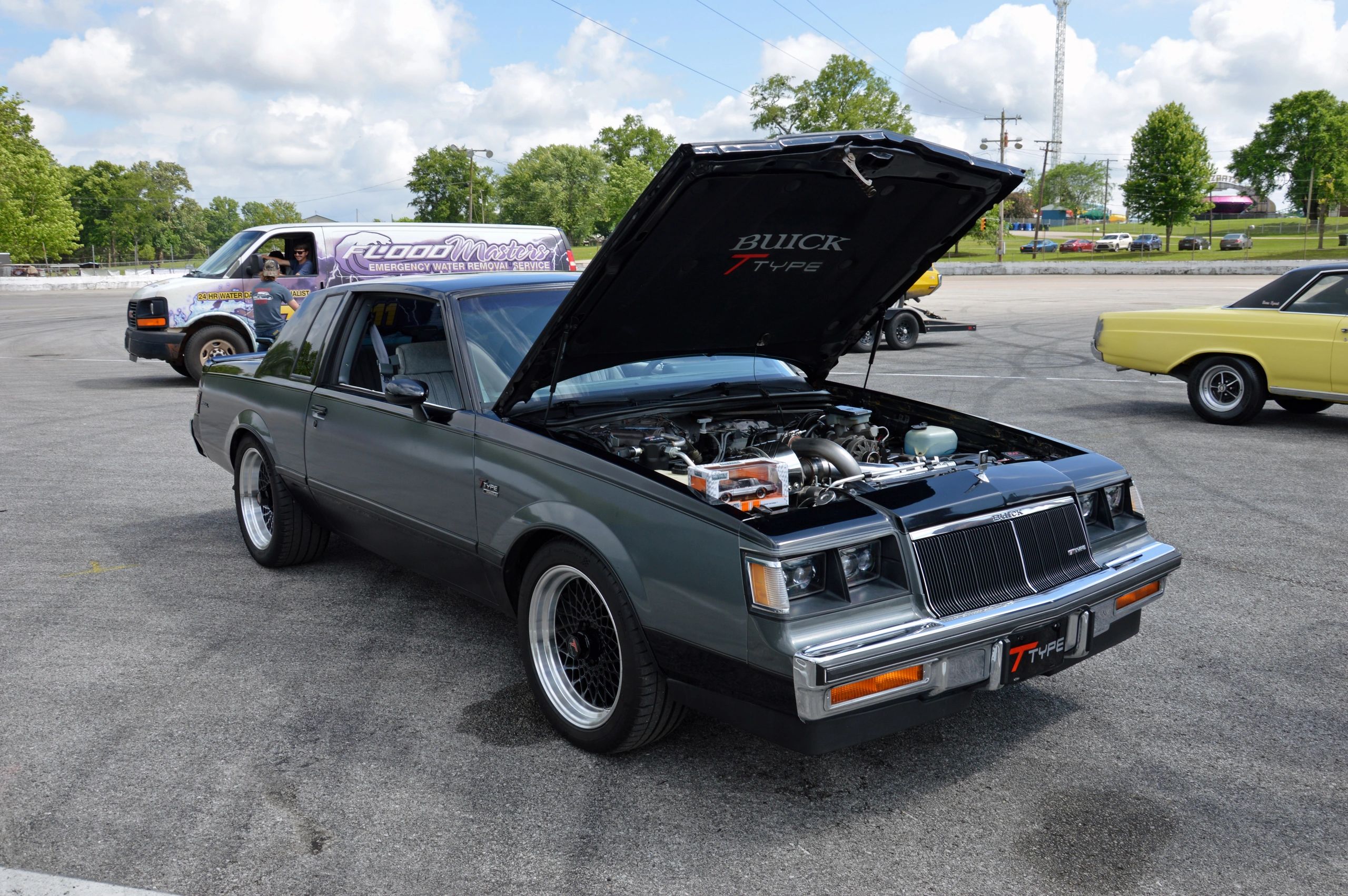 Classic Buick T-Type with open hood on a sunny day at a car meet.