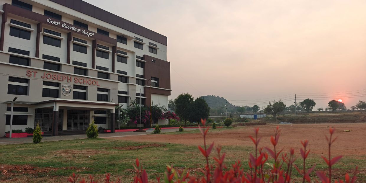 St Joseph School building with a sunset and hill in the background.