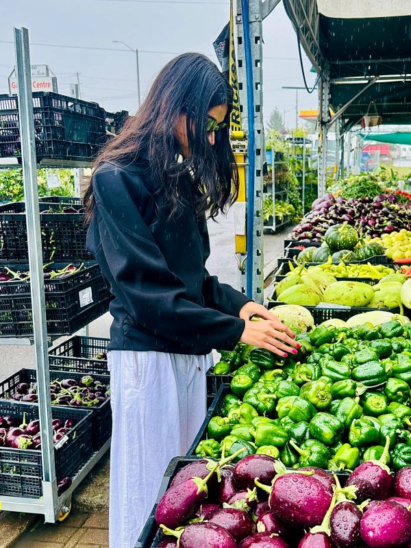 Woman selecting green bell peppers at a market.
