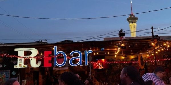 Evening scene at ReBar with colorful lights and Stratosphere Tower in background.