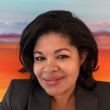 Woman smiling with a colorful sunset background.