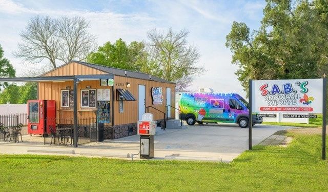 A colorful snowball shop with a vibrant van parked outside.