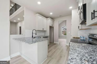 Modern kitchen with granite countertops and white cabinets.