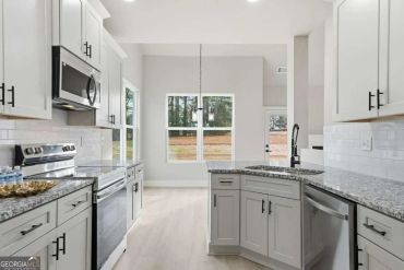 Bright modern kitchen with granite countertops and white cabinetry.