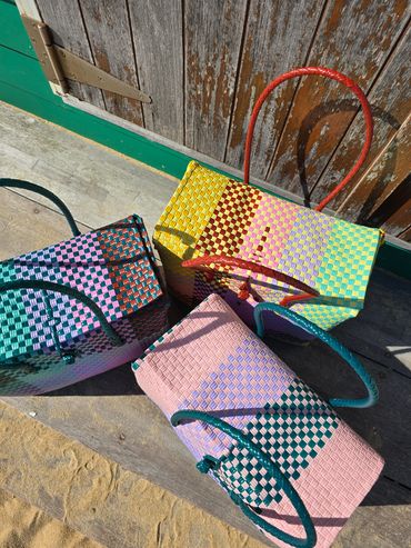 Colorful woven handbags with patterned designs displayed outdoors.