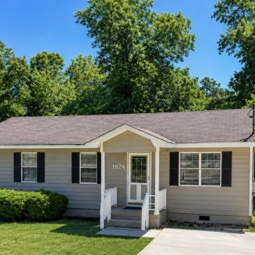 Single-story suburban house with gray siding and black shutters.