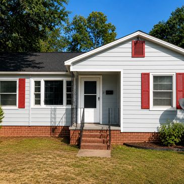 White house with red shutters and a small front porch.