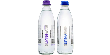 A clear glass filled to the brim with fresh and pure drinking water. The glass sits on a clean, whit
