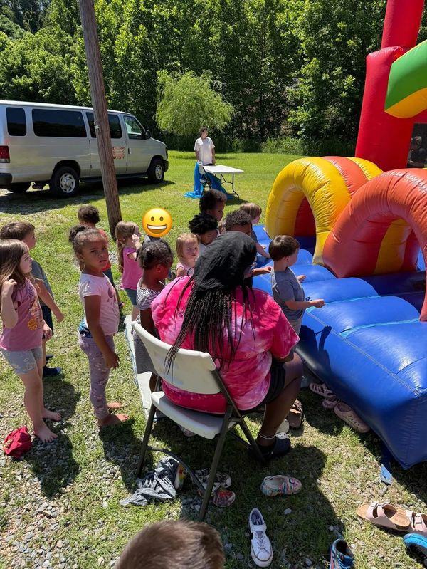 Children waiting in line for an inflatable play structure on a sunny day.