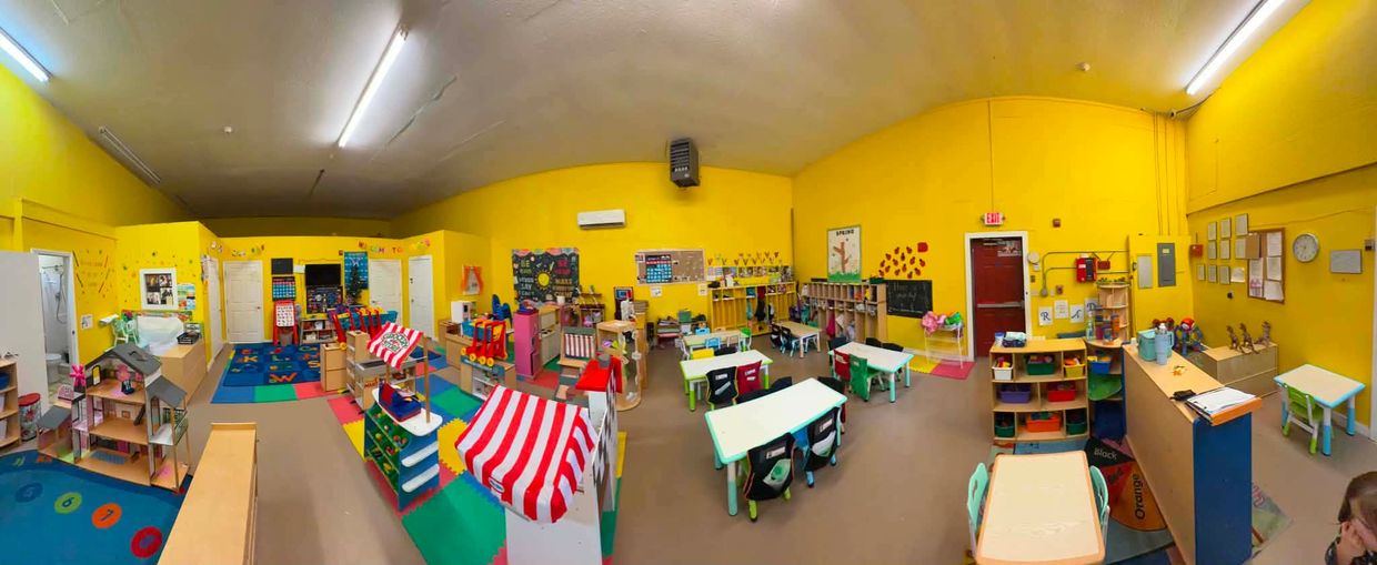 Bright and colorful preschool classroom with toys and small tables.
