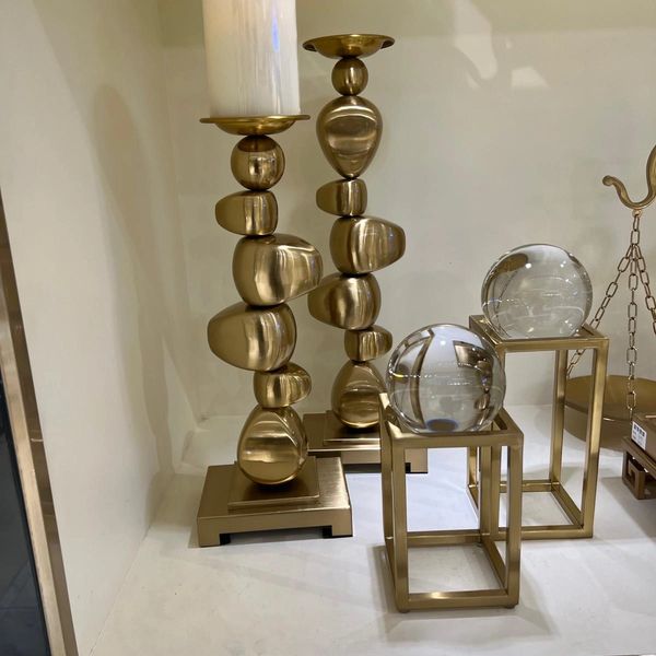 Modern gold candle holders and glass spheres on geometric stands.