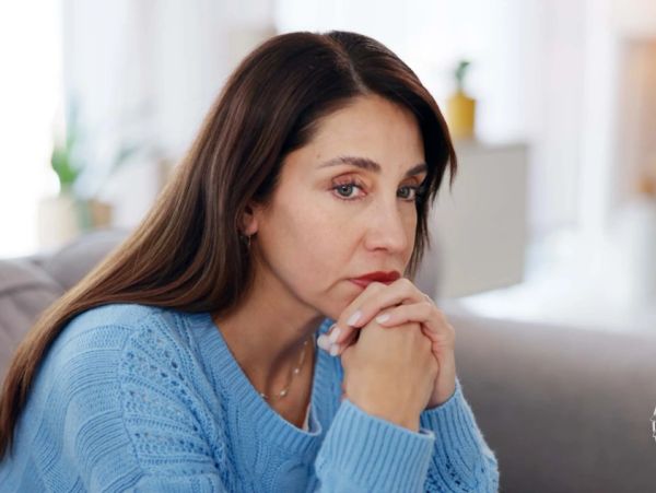 A woman looking thoughtful and reflective indoors.