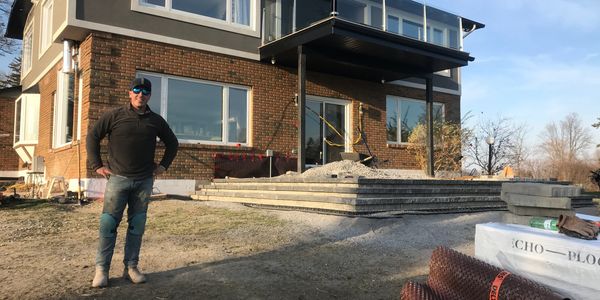 Man standing in front of a brick house under construction with concrete steps.