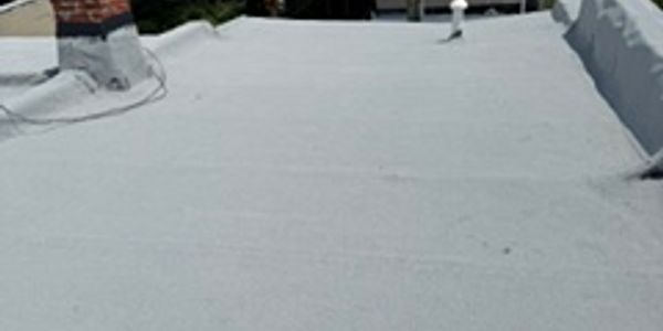 Flat rooftop with white coating and chimney.