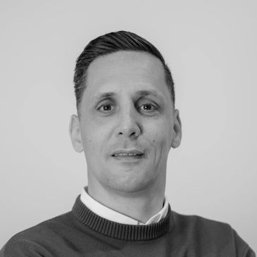 Black and white portrait of a man with short hair wearing a sweater.