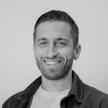 Smiling man with short hair and beard in a casual shirt.