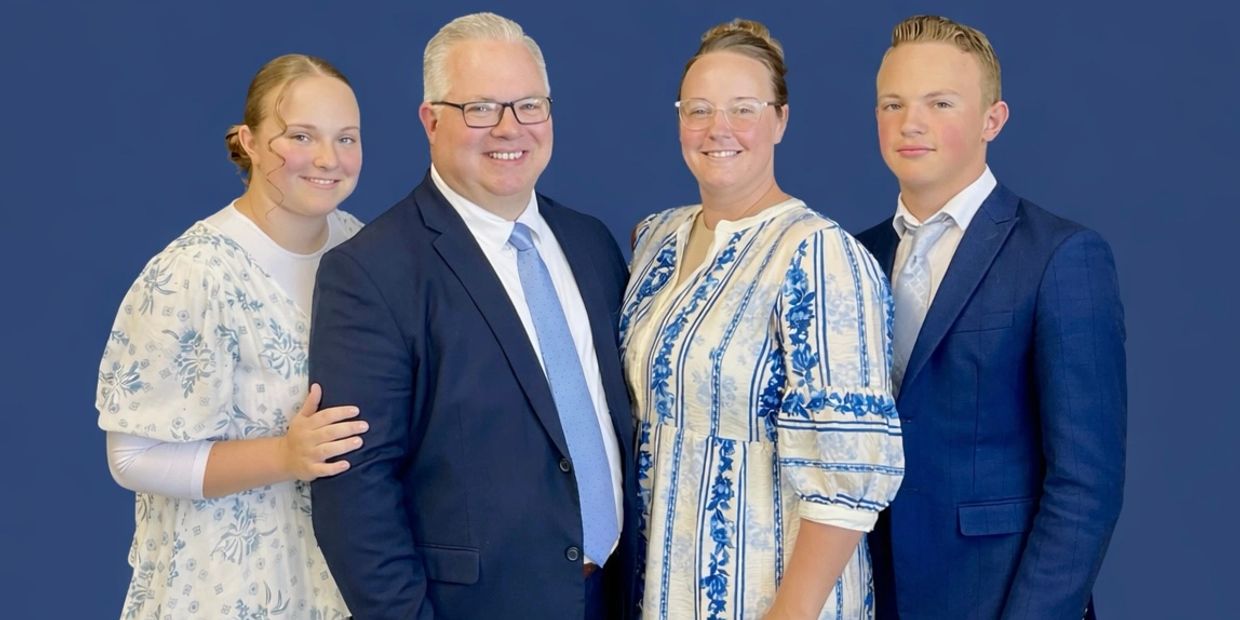 A well-dressed family of four posing against a blue background.