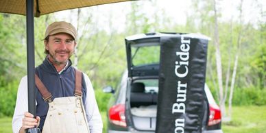 Man in overalls selling Aaron Burr Cider outdoors.