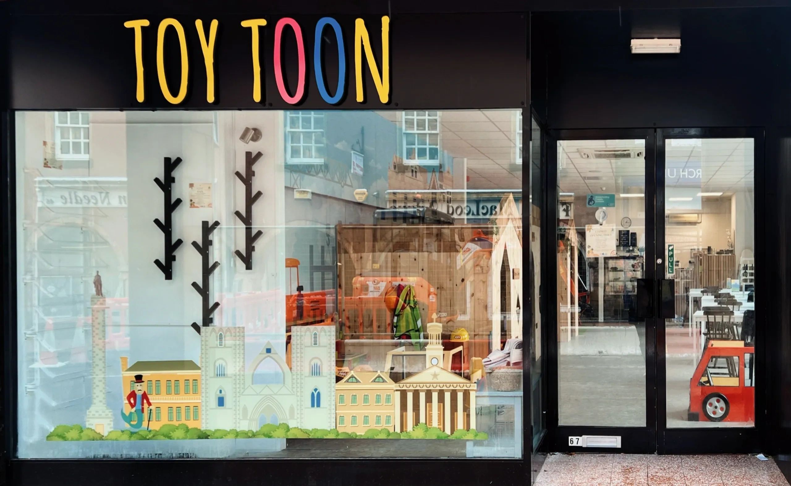 A black shop front with coloured writing saying Toy Toon. 