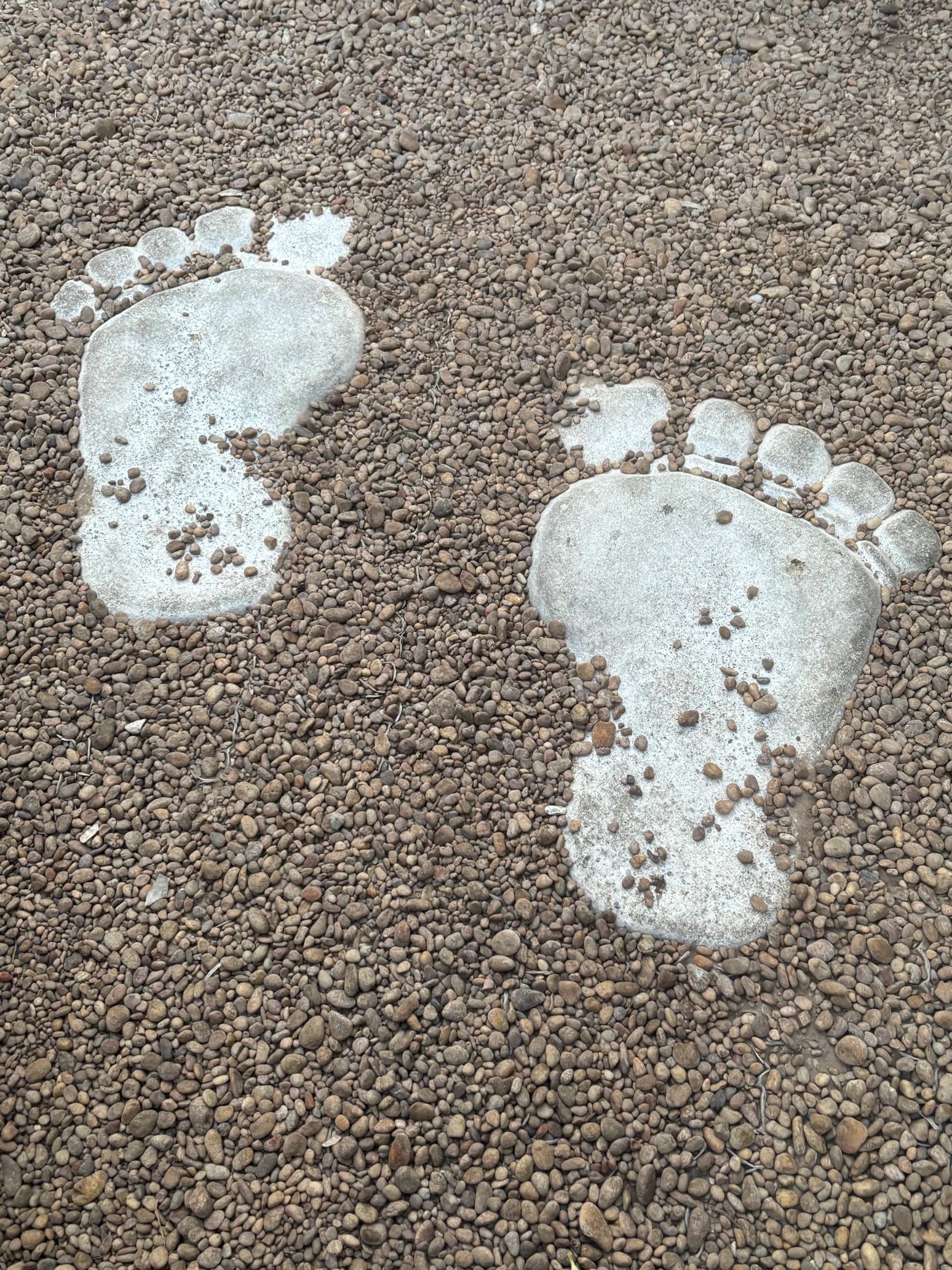 Concrete footprints embedded in a gravel path.