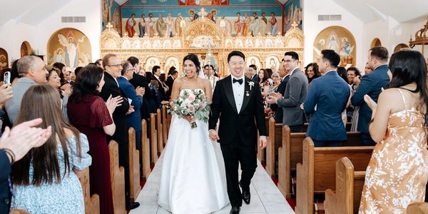 Newlywed couple joyfully walking down the aisle in a decorated church.