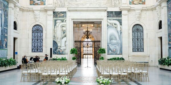 Elegant white marble hall set for a ceremony with musicians playing.