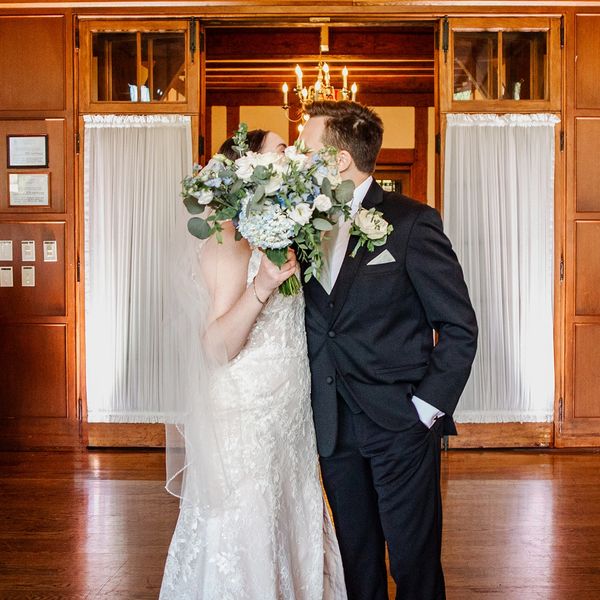 couple kissing behind bouquet