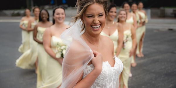 Bride joyfully poses with bridesmaids in matching yellow dresses outdoors.