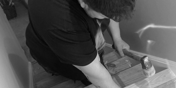 Caleb pound a stair tread into place with a rubber mallet.