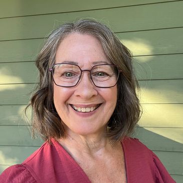 Smiling woman with glasses and shoulder-length hair.
