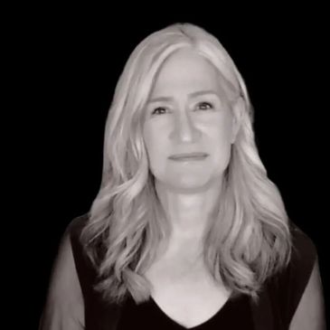 Portrait of a woman with long blonde hair against a black background.