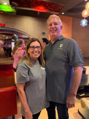 A smiling couple posing indoors in casual attire.