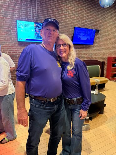 Couple in matching blue shirts posing indoors with smiles.