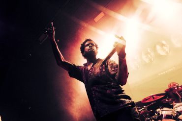 Musician passionately performing on stage under dramatic lighting.