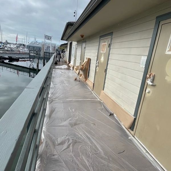 Boardwalk with plastic covering and doors along a waterfront.