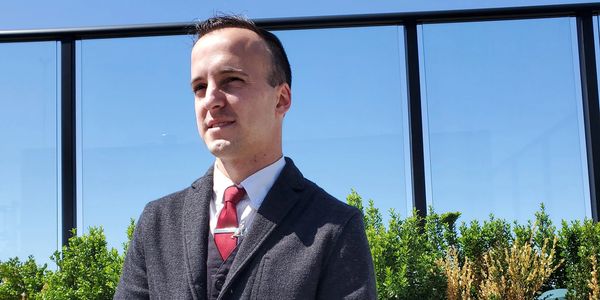 Man in a suit outdoors on a sunny day.