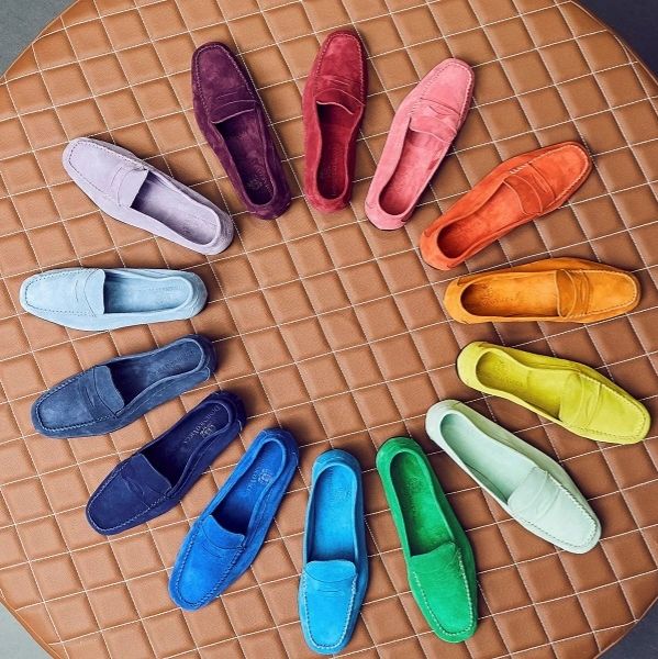 Colorful loafers arranged in a circular pattern on a quilted surface.