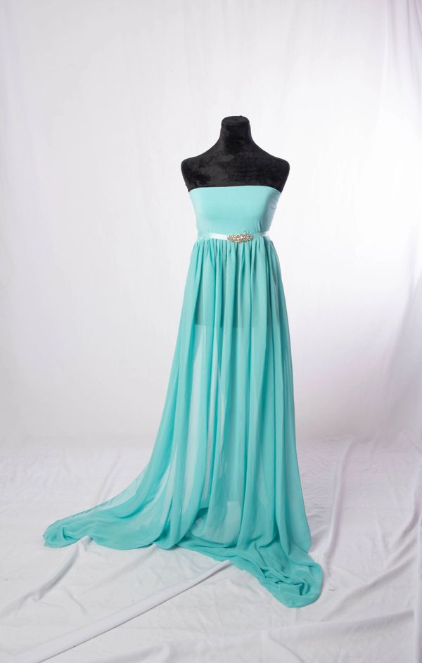 Elegant strapless light blue gown with flowing sheer skirt and jeweled belt on black mannequin.
