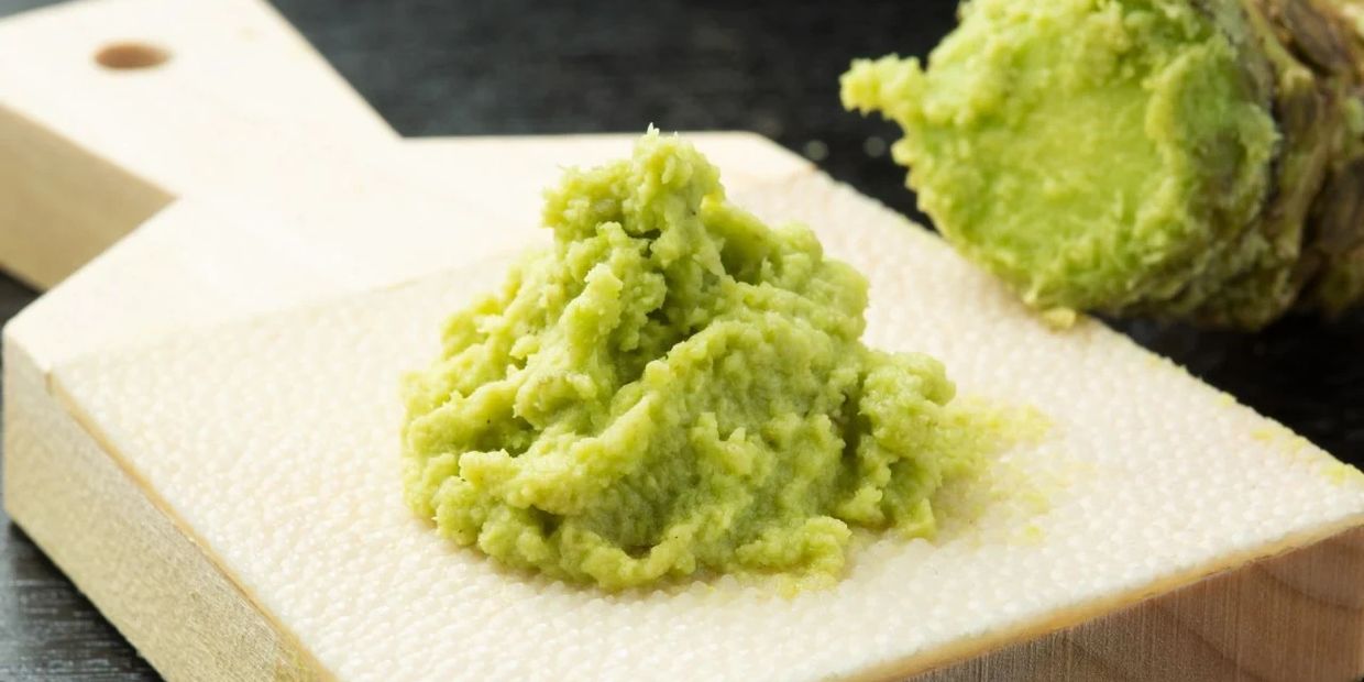 Fresh green wasabi paste on a wooden board with wasabi root.